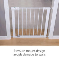 White pressure-mount baby gate on a wooden floor with text indicating it avoids wall damage.